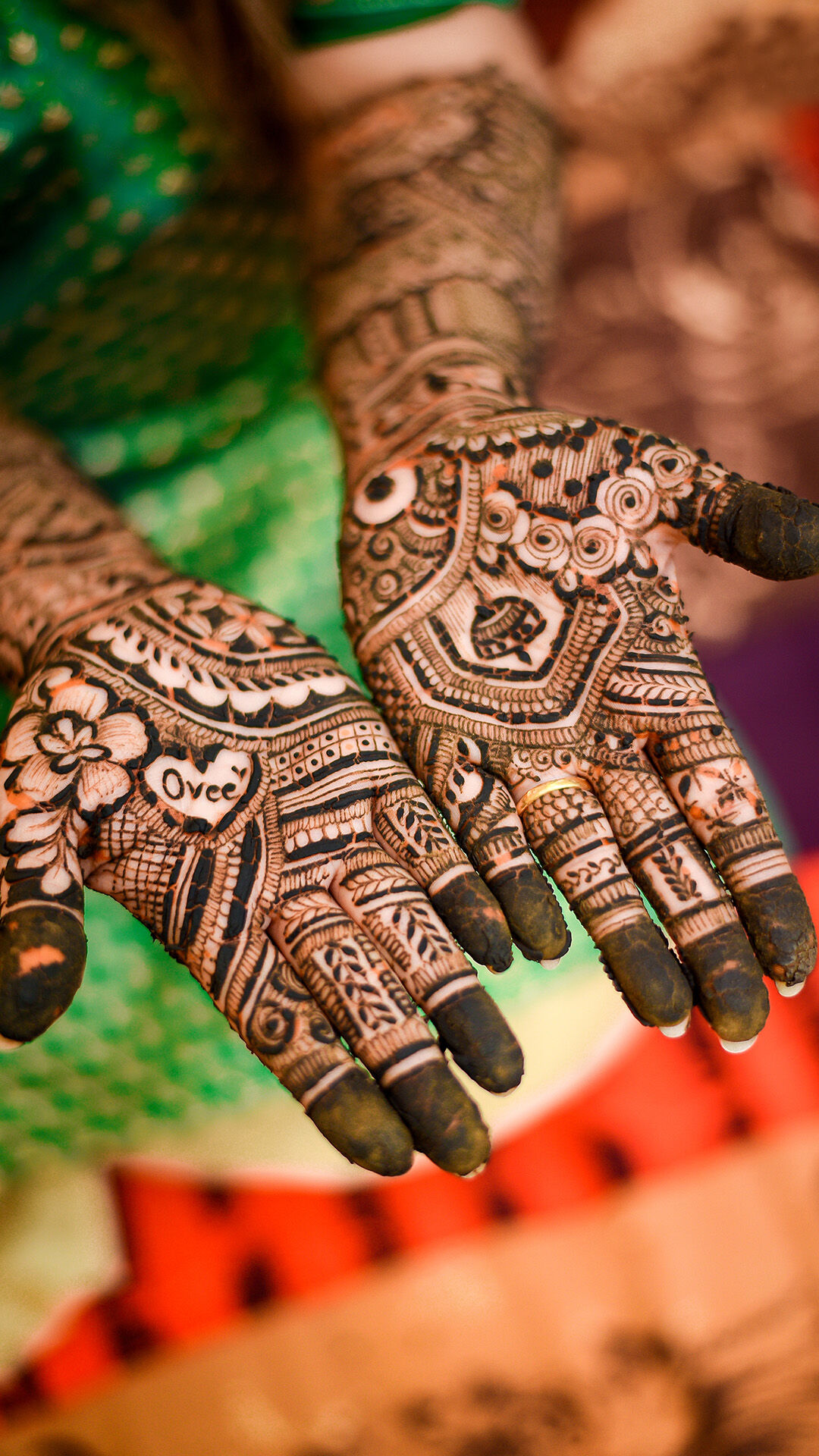 A bride elegantly displaying her bridal mehendi, featuring the groom’s name intricately woven into the design